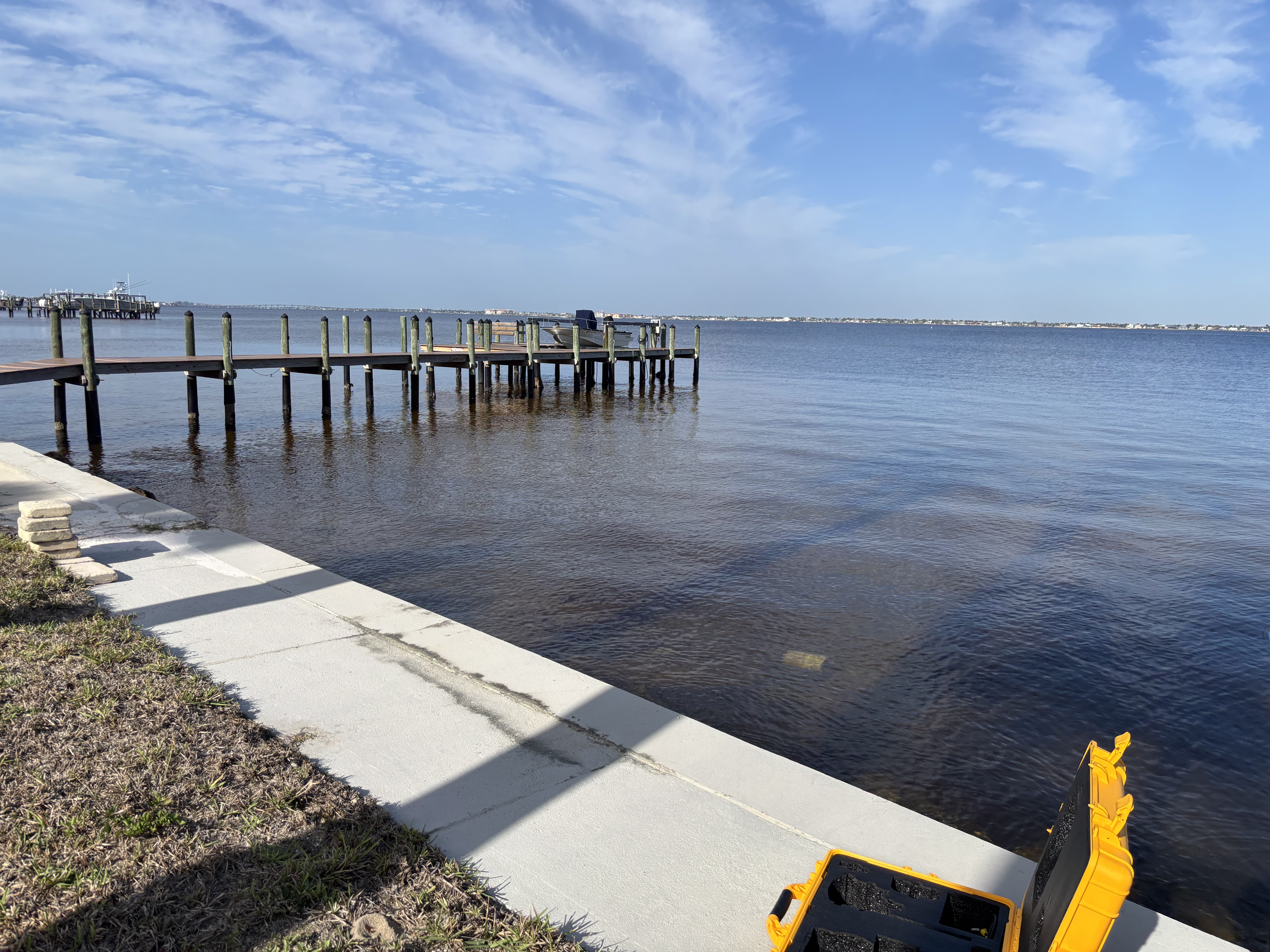 Shoreline stabilization project — seawall edge with excavator equipment along a Florida bay